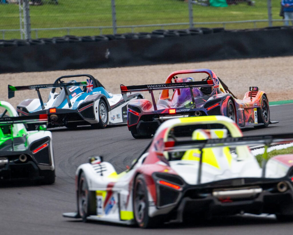 Car, driven by either Bradley Gaunt or Ashley Gaunt, rounding a corner on a race track with other race cars visible around it.